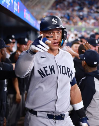 Aaron Judge #99 of the New York Yankees celebrates in the dugout after hitting a 2 run home run in the eighth inning during a game against the Toronto Blue Jays at Rogers Centre on July 02, 2025 in Toronto, Ontario, Canada.